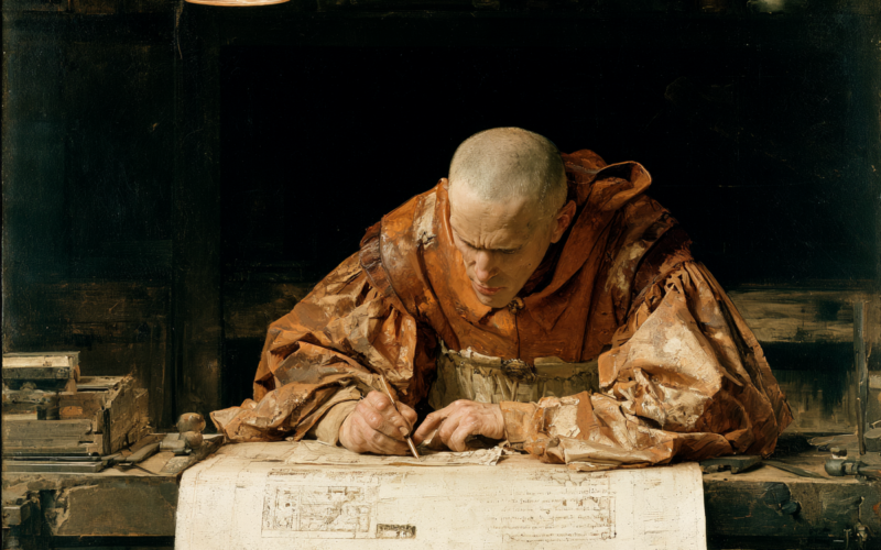 Monk-like man in orange robes studies architectural plans at a drafting table, pencil in hand, in a dim workshop.
