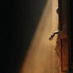 Metal humanoid robot peeking from a partially opened wooden door, illuminated by a warm beam of light with dust particles in the air.